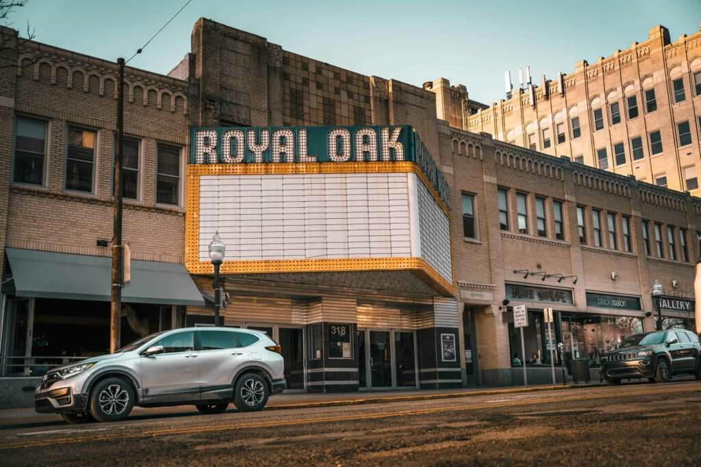 Street view of a brick building with a vintage Royal Oak Theater sign near shops in Royal Oak, MI