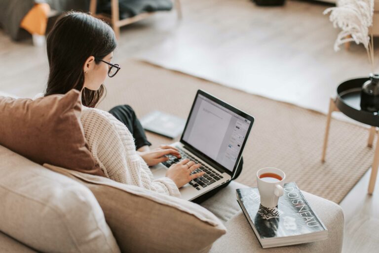 Woman sitting on couch on laptop.