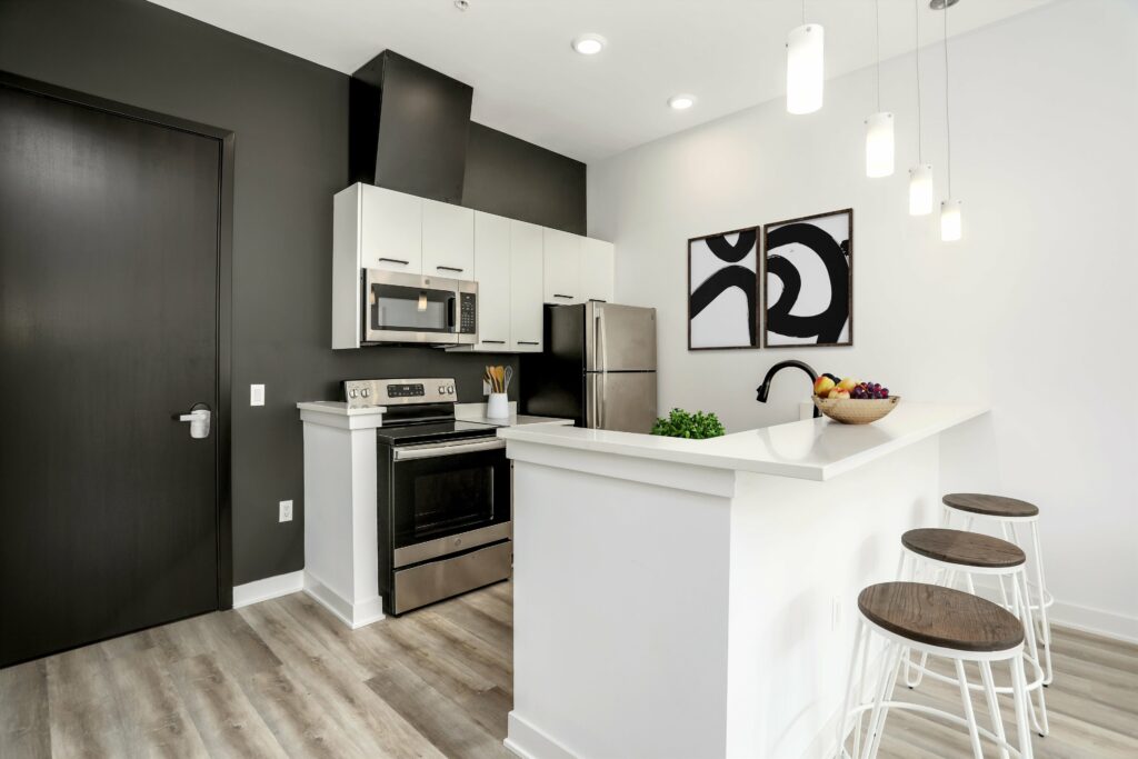 Kitchen with hard floors, stainless steel appliances, and an L-shaped bar near the entrance door