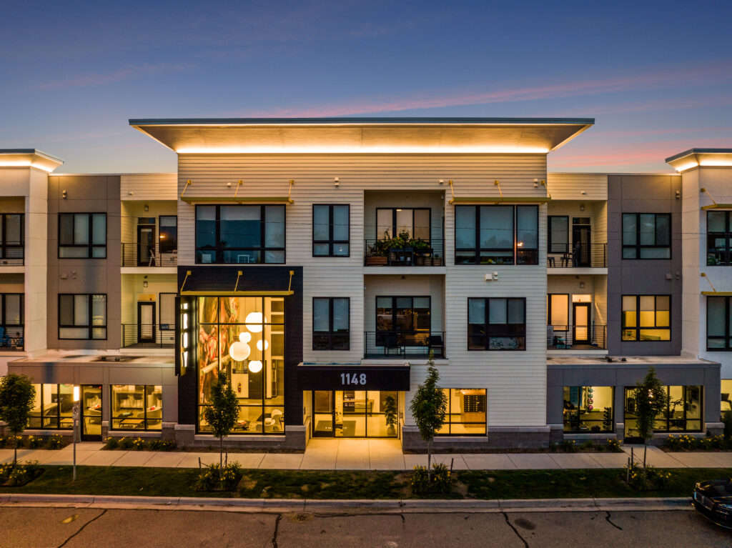 Beautifully lit exterior street view of The Roy Apartment units, clubhouse, and lobby at dusk